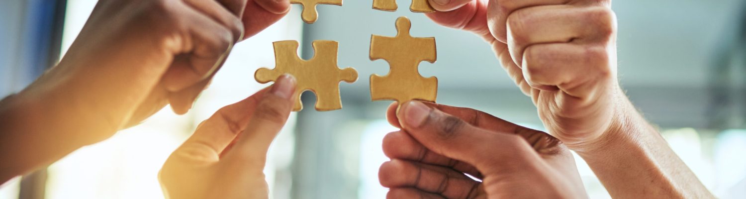 Group of business people holding puzzle pieces. Professionals connect and collaborate together inside office building. Closeup of hands, and team working together on a new strategy for success.